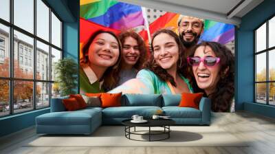 Cheerful selfie of a group of LGBTQIA people in a pride parade, looking at camera smiling holding rainbow flags. Concept of Supporting the Homosexual community. Wall mural