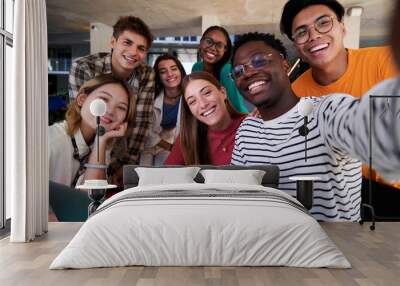 Happy selfie of a multiethnic group of student friends gathered at university studying in the cafeteria, looking at camera smiling. Wall mural