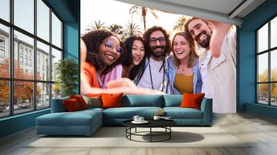 Happy selfie of an internacional group of friends making frame gesture with fingers during their beach holidays outdoors. People looking at camera smiling. Wall mural