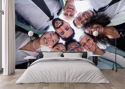 Multiethnic group of work colleagues embraced in circle, face down taking a selfie smiling and looking at the camera. Vertical image, POV business people doing team building.  Wall mural