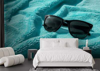 Black sunglasses on a turquoise towel outdoors Wall mural