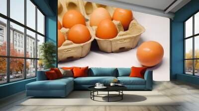 Cardboard egg boxes with seven brown eggs on a white background, but one egg is outside the box. Wall mural