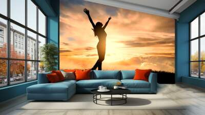 free and happy woman raises her arms at sunset. Have a positive mindset. Wall mural