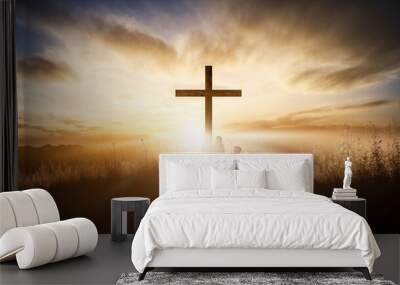 People praying under the wooden cross on the hill at sunset Wall mural