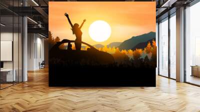 young woman comes out of the sunroof of her electric car to enjoy the sunset over the woods. Have a positive mindset. Wall mural