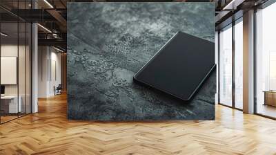 Dark tablet resting on a cement surface Wall mural