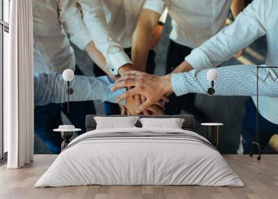 Group of young business people putting their hands on top of each other. Wall mural