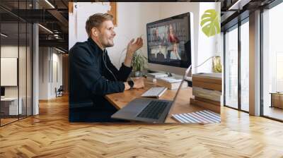 Young man having Zoom video call via a computer in the home office. Stay at home and work from home concept during Coronavirus pandemic. Smiling handsome man teleworking Wall mural