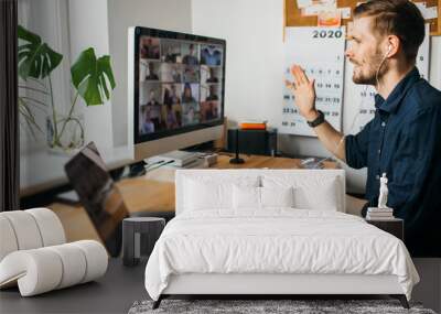 Young man having Zoom video call via a computer in the home office. Stay at home and work from home concept during Coronavirus pandemic. Wall mural