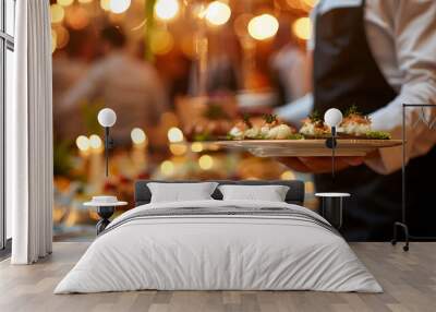 Close-up of a waiter holding a plate of appetizers at an elegant dinner party, with festive lighting and a beautifully set table in the background. Wall mural