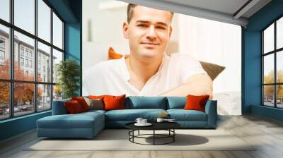 Confident man relaxing at home in living room Wall mural