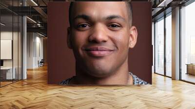 Studio portrait of young man smiling and posing on brown backgro Wall mural