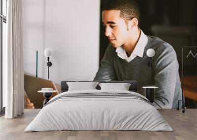 Young man working from home using laptop computer at desk Wall mural