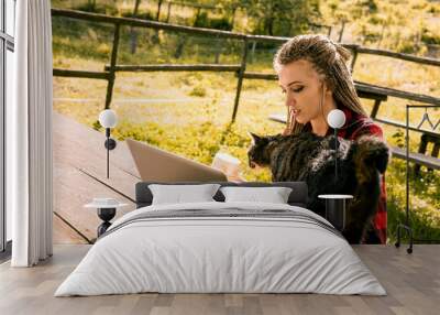 Young woman working remotely in nature with her cat Wall mural