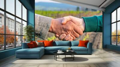 a handshake between two farmers with the background of cultivated fields Wall mural