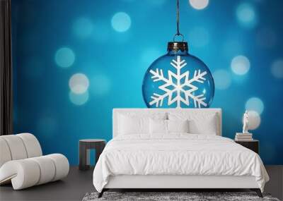 Glass Christmas ornament with white snowflake pattern hanging on a blue background with soft glowing lights. Winter holiday decoration and festive season concept Wall mural