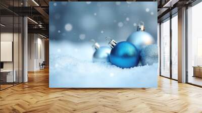 The detailed view showcases a shimmering silver and blue holiday decoration resting on soft, white snow, creating a festive winter atmosphere. The bokeh effects enhance the sparkling element Wall mural