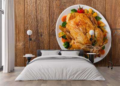 Roast chicken whole. Served on a plate with vegetables and baked potatoes. Wall mural