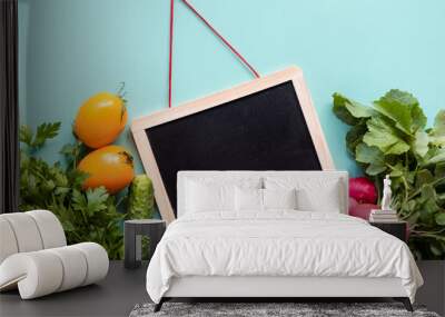 Helthy concept. Fresh vegetables around black desk on blue background. Wall mural