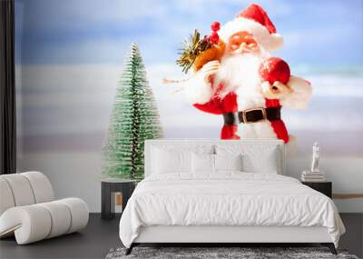 Toy Santa Claus on the beach against the background of the azure sea and blue sky. Copy space Wall mural