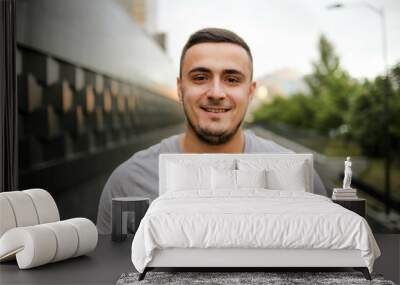 Young smiling jewish man wearing gray t shirt walking on the street. Handsome young man looking at camera. Wall mural