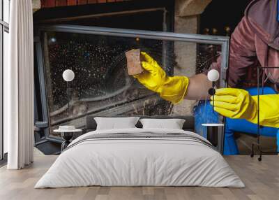 Hands in yellow gloves wash glass fireplace door Wall mural