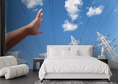 hands reach for power transmission lines against blue sky Wall mural