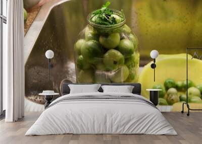 Large glass jar with green tomatoes stands in sink Wall mural