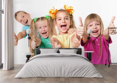 Group of happy kids with thumb up sign in colorful t-shirts standing together - isolated on white. Wall mural