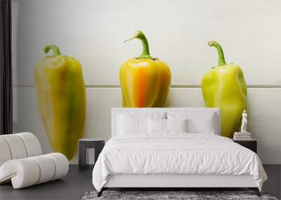 Three green fresh bell peppers on a white wooden background Wall mural