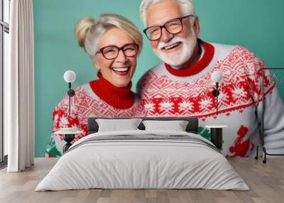 An elderly couple dons festive christmas sweaters, their smiles beaming with holiday cheer as they stand against a wall adorned with twinkling lights, their glasses reflecting the love of the season Wall mural