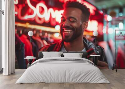 Smiling young man holding a credit card, shopping in a clothing store with neon lights Wall mural