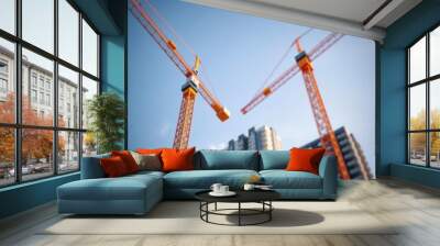 Close-up of two tower cranes working against the backdrop of a new building and blue sky selective focus Condominium   Wall mural