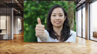 Mixed race Asian girl thumb up with nature background Wall mural