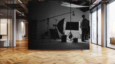 Behind the scene of photo shooting and production set up in the big studio. Professional crew team working and camera equipment in silhouette. such as light box, tripod, flashlight. and copy space. Wall mural