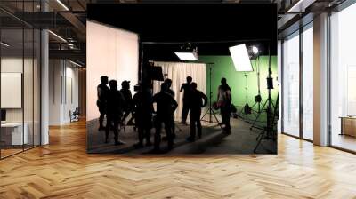 Behind the scenes of TV commercial movie film or video shooting production which crew team and camera man setting up green screen for chroma key technique in big studio. Wall mural