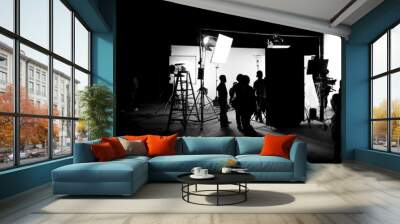 Silhouette images of video production behind the scenes or b-roll or making of TV commercial movie that film crew team lightman and cameraman working together with director in big studio Wall mural