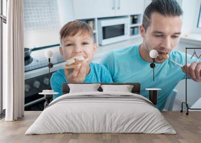 happy kid boy and father eating healthy peanut butter toast at home kitchen Wall mural