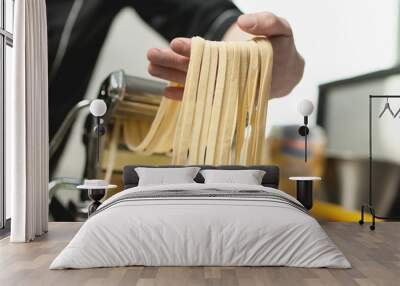 human hand with pasta from machine; Wall mural