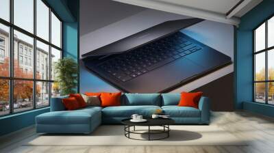 Sleek Dark Laptop: A captivating close-up showcasing a modern dark-grey laptop with its lid slightly ajar, subtly illuminated by a cool blue glow. Wall mural