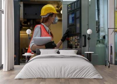 Portrait of female technician engineer control machines in the factory on a business day. Confident worker wearing particulate respirator mask with hard hat. Concept of Industrial manufacturing. Wall mural