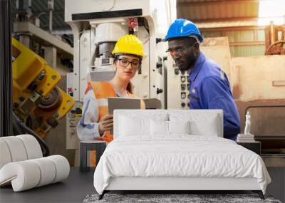 Supervisor, worker with hard hat working in manufacturing factory on business day. Female industrial engineers have to consult with colleagues while using tablet. Concept of workplace gender equality Wall mural