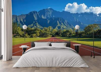 A red running track leads towards a mountain range, with palm trees lining the edge of the grass. Wall mural