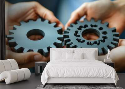 Two hands holding two interlocking cogs, representing teamwork, collaboration, and success. Wall mural