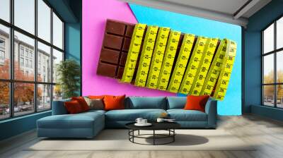 Diet concept. Losing weight concept. Chocolate and yellow measuring tape on a colored background Wall mural