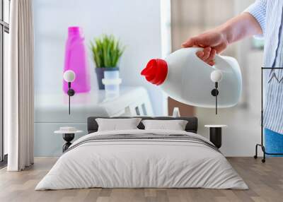 Female housewife pouring fabric softener gel into a modern washing laundry machine Wall mural