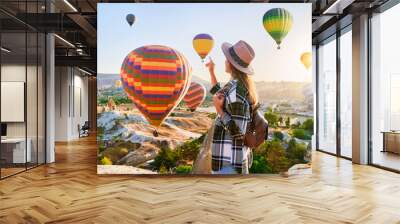 Girl traveler vacations in beautiful destination in Goreme, Turkey. Fabulous Kapadokya with flying air balloons at sunrise, Anatolia Wall mural