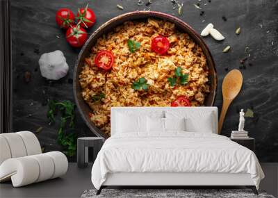 Homemade delicious pilaf with chicken, fresh parsley and ripe vegetables in a pan for lunch on a dark background. Top view Wall mural