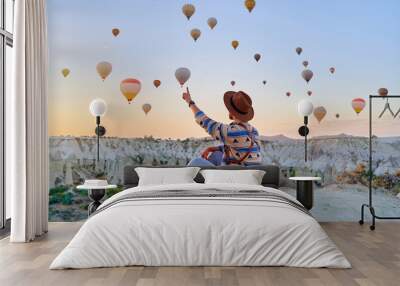 Man traveler vacations beautiful destination in Goreme, Turkey. Fabulous Kapadokya with flying air balloons at sunrise, Anatolia Wall mural