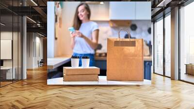 Modern busy cute smiling joyful happy casual millennial woman received cardboard bags and paper cups with takeaway food and drinks. Fast home delivery concept Wall mural